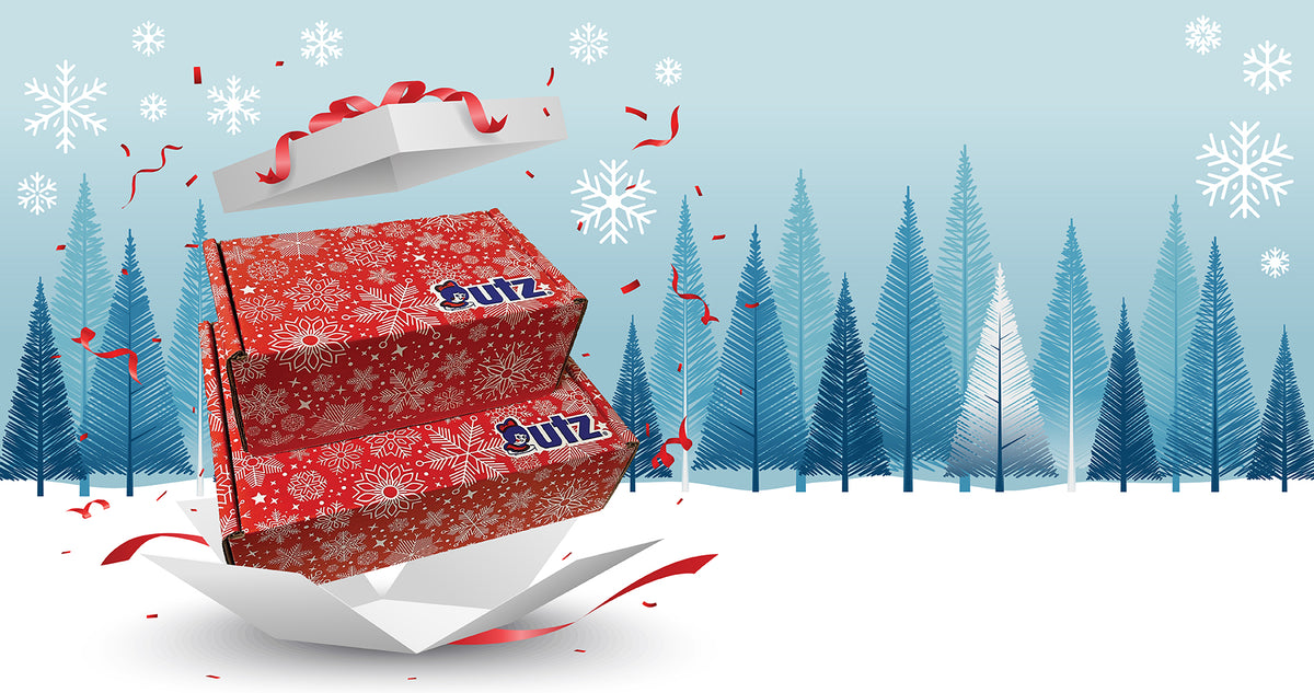 Two red Utz gift boxes with a white snowflake pattern burst from an open present in a snowy pine forest